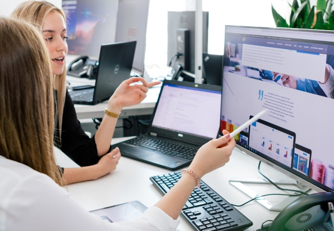 Zwei Mitarbeiter betrachten ein Webdesign auf einem Rechner