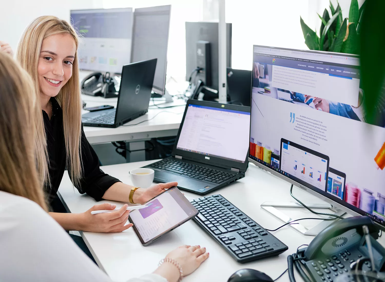 Zwei Mitarbeiterinnen gehen auf einem Tablett ein Projekt durch