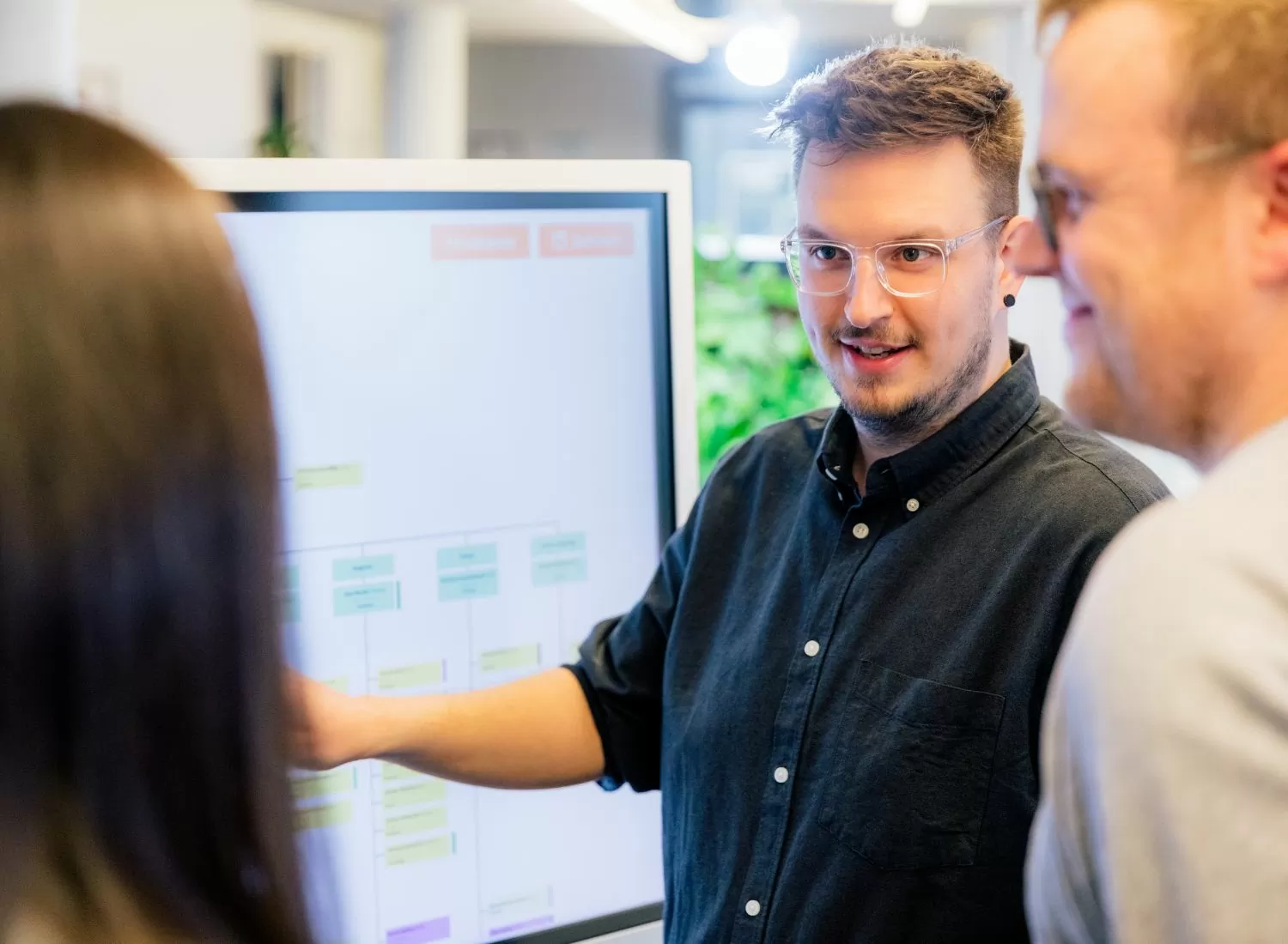 Mitarbeiter besprechen Informationen an einem großen Bildschirm