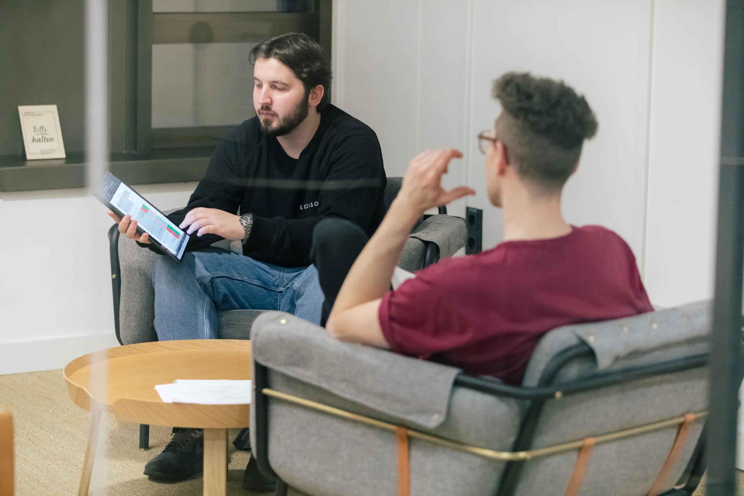 Ihre Digitalagentur in Frankfurt am Main Zwei Mitarbeitende sitzen in einer Lounge und unterhalten sich.