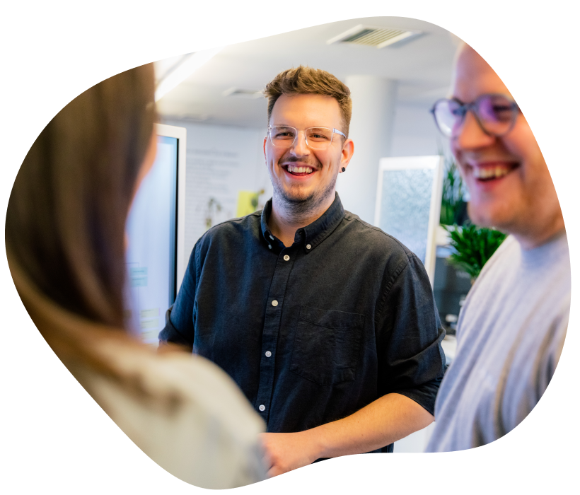 Drei Personen besprechen sich geschäftlich vor einem großen Bildschirm