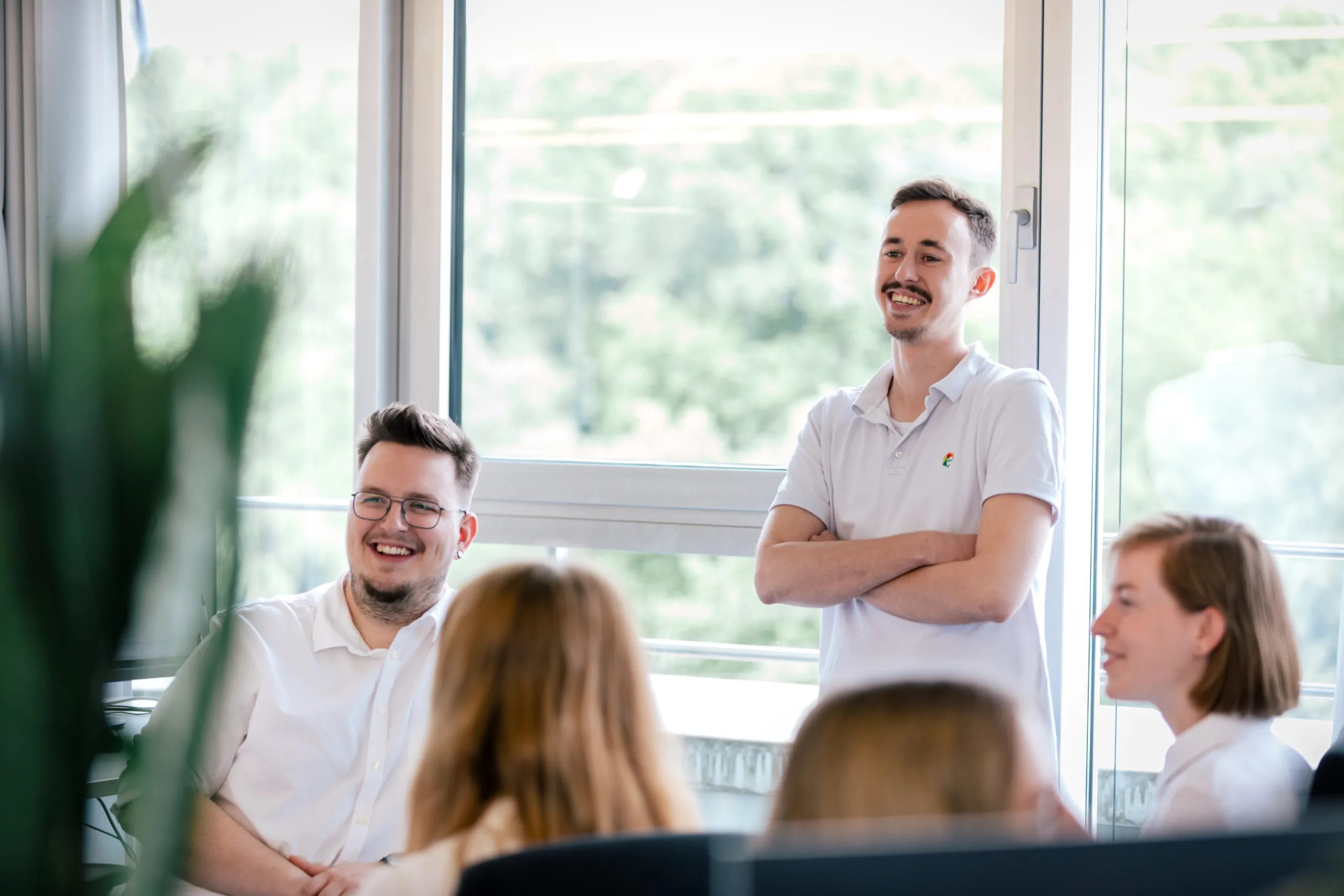 Mehrere Mitarbeiter sitzen lächelnd zusammen und reden