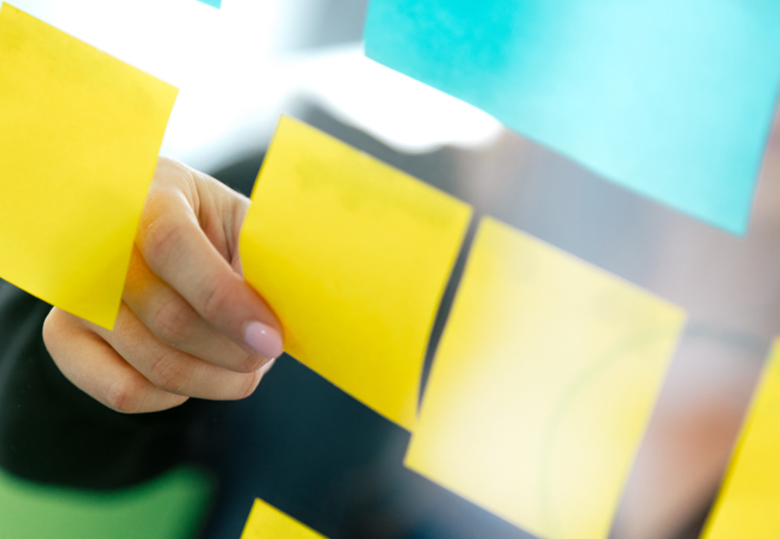 blog_econsor_Customer-Lifetime-Value Eine Person hält ein Blatt Papier mit bunten Haftnotizen in der Hand.