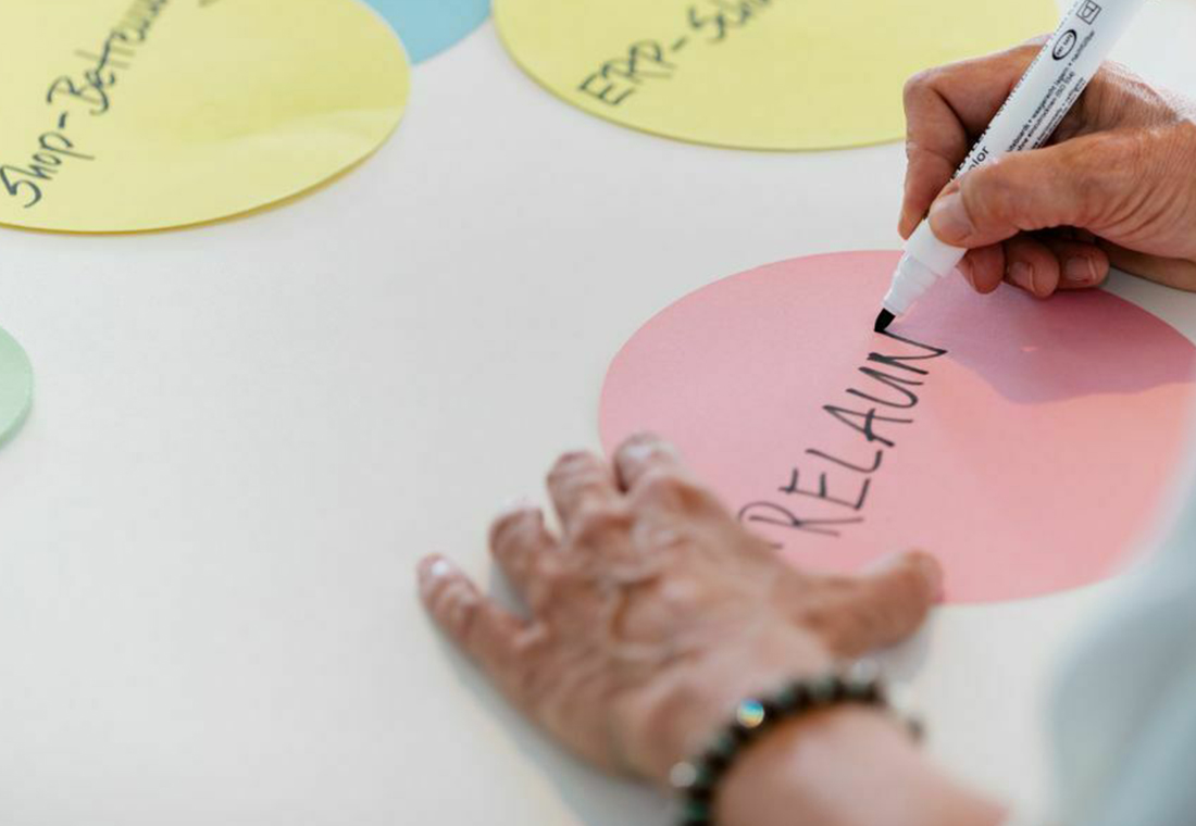 Eine Person schreibt mit Markern auf ein Blatt Papier.