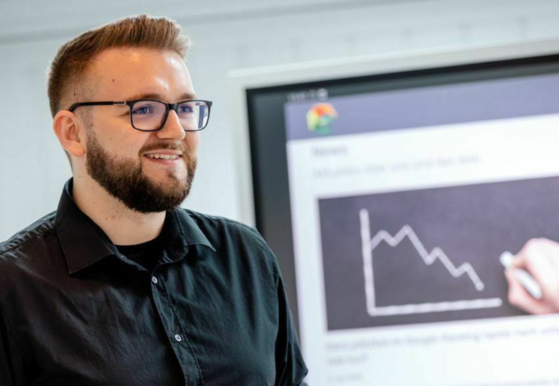 blog-econsor-google-ranking-rapide-sinkt Ein Mann mit Brille und Bart steht vor einem Display und schaut in die Kamera.