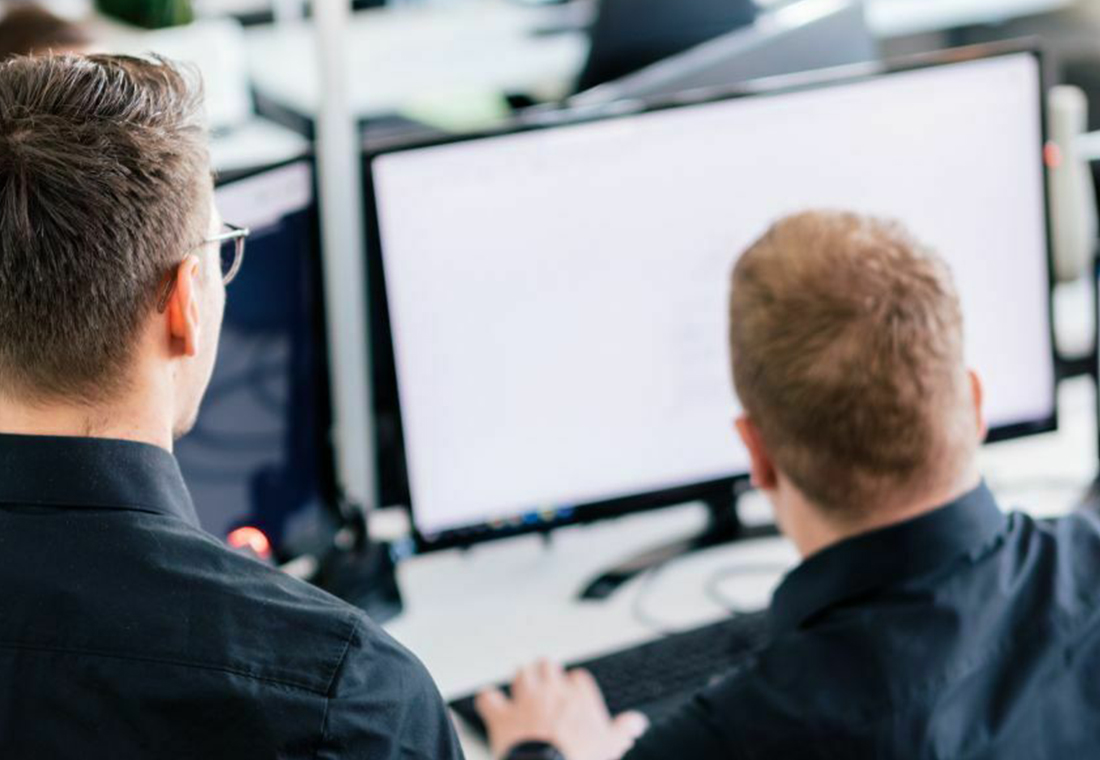 integrierte-marketinganalysen Zwei Männer in schwarzen Hemden sitzen an Computern und arbeiten konzentriert an ihren Bildschirmen.