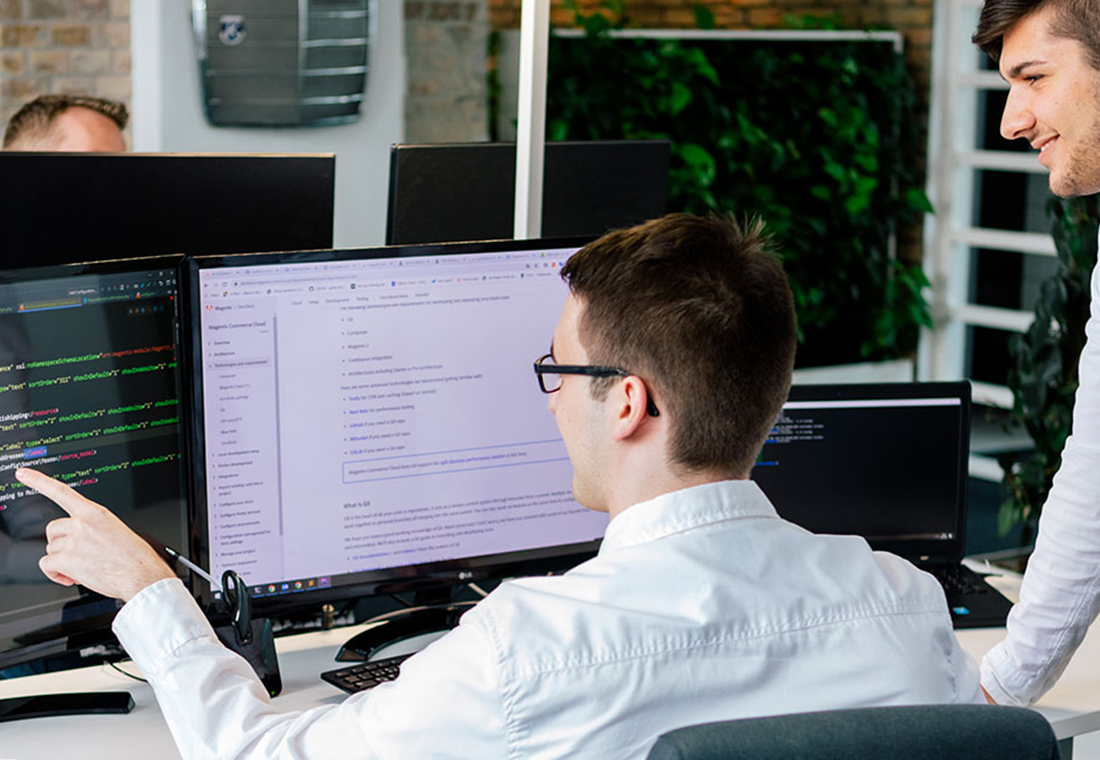 top-10-typo3-erweiterungen Zwei Männer schauen auf einen Computerbildschirm und scheinen sich über den Inhalt auszutauschen.