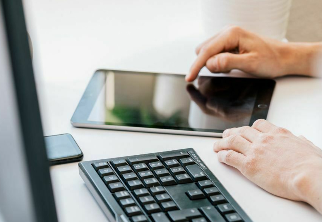 Eine Person arbeitet an einem Tisch mit einem Tablet und einer angeschlossenen Tastatur.