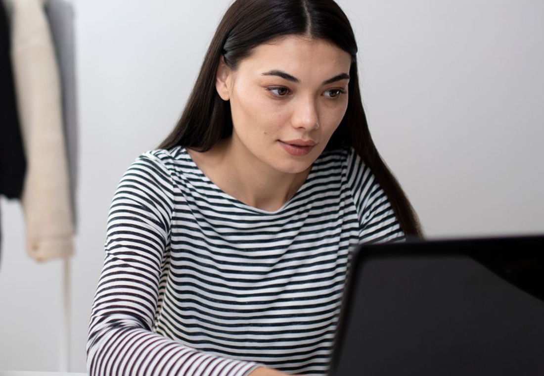 Frau-am-pc-ecommerce Frau sitzt am PC umgeben von Kartons und Kleidung