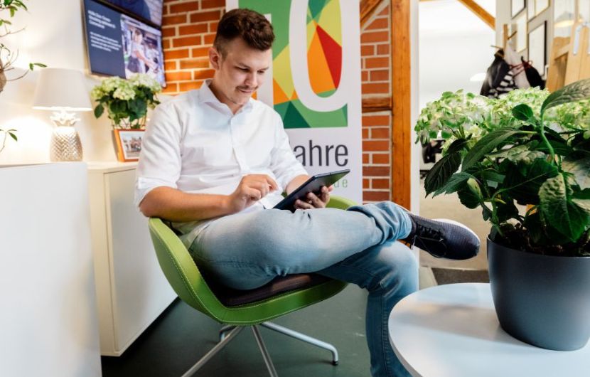 Ein Mitarbeiter sitzt auf einem Stuhl und benutzt ein Tablet