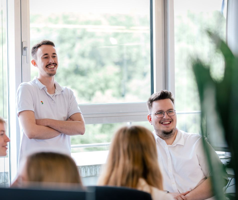 Mitarbeiter befinden sich in einem Besprechungszimmer und lächeln