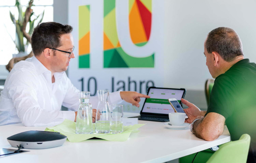 Kundenberatung Ein Mitarbeiter zeigt einem Kunden die Möglichkeiten mit Adobe Commerce