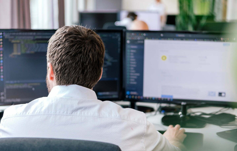 Ein Mitarbeiter sitzt an seinem Arbeitsplatz in der Shopware-Agentur