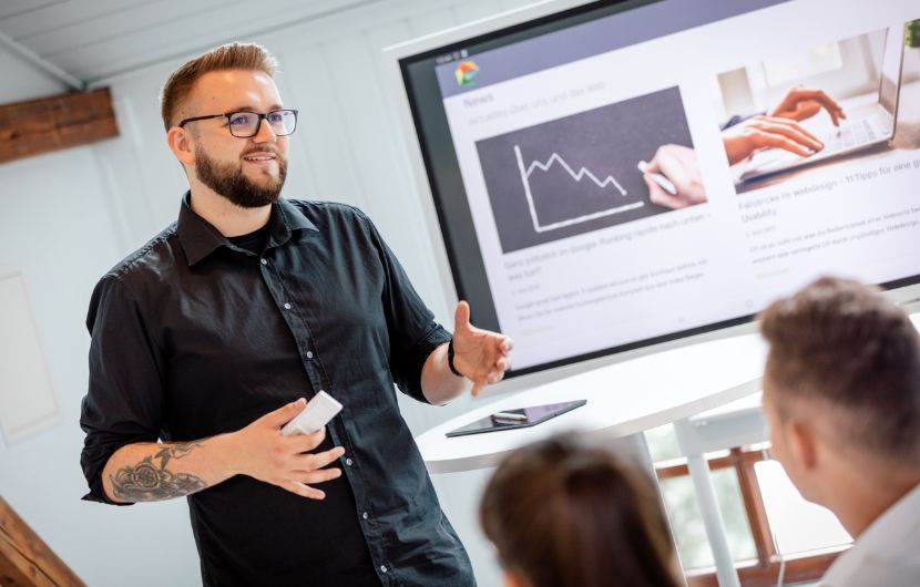 Praesenation-der-Ergebnisse–scaled Ein Mitarbeiter hält eine Präsentation