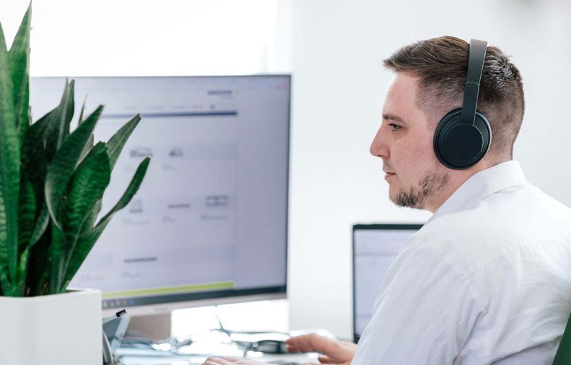 TYPO3-arbeitsplatz Ein Entwickler einer TYPO3-Agentur arbeitet konzentriert mit Headset am Bildschirm – für individuelle Weblösungen mit TYPO3.