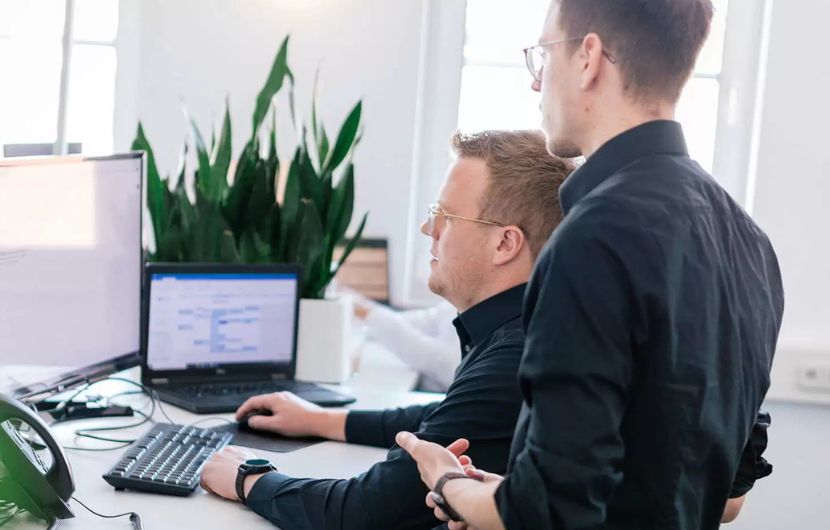 Zertifizierte Google-Ads SEA-Agentur Ein Team von SEA-Experten in einem modernen Büro, umgeben von Zertifikaten und digitalen Bildschirmen, diskutiert angeregt Strategien für Google Ads Kampagnen – Symbol für eine zertifizierte Google-Ads SEA-Agentur.