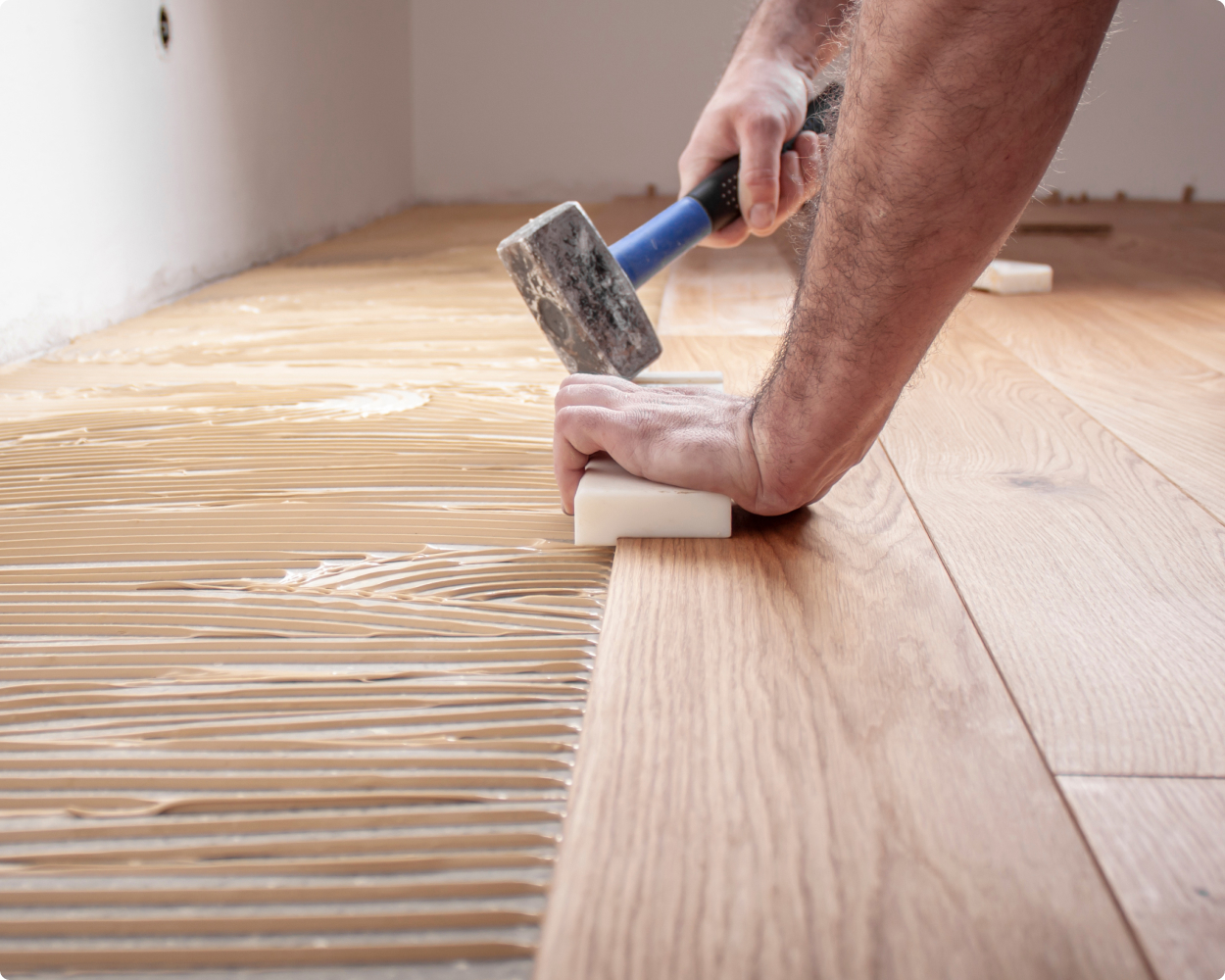 Ein Laminatverleger verlegt in einer Wohnung Bembe Parkett auf dem Boden.