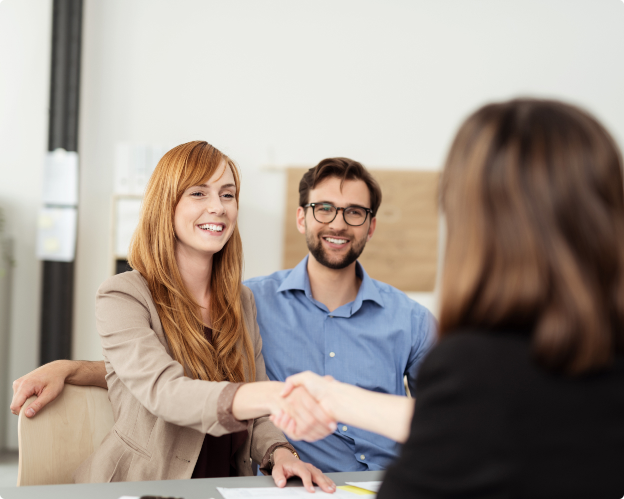 Ein Paar sitzt einer Anwältin von boehmert und boehmert gegenüber, während die Frau und die Anwältin Hände schütteln.