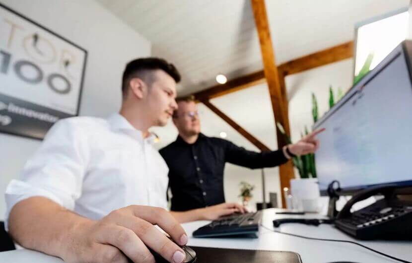 Conversion-Rate im B2B Zwei Kollegen sitzen an einem Bildschirm und optimieren die Conversion-Rate eines B2B-Kunden