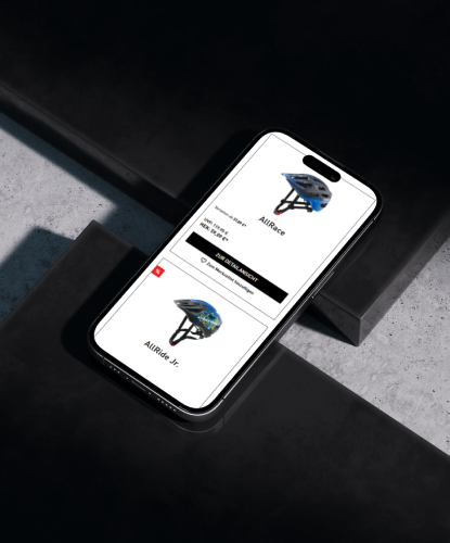 cratoni-shop-bilderreihe-1 Ein Smartphone liegt flach auf einer dunklen Oberfläche. Auf dem Bildschirm des Smartphones ist der Cratoni-Shop abgebildet.