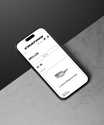 cratoni-shop-bilderreihe-3 Ein Smartphone liegt flach auf einer hellen Oberfläche. Auf dem Bildschirm des Smartphones ist der Cratoni-Shop abgebildet.