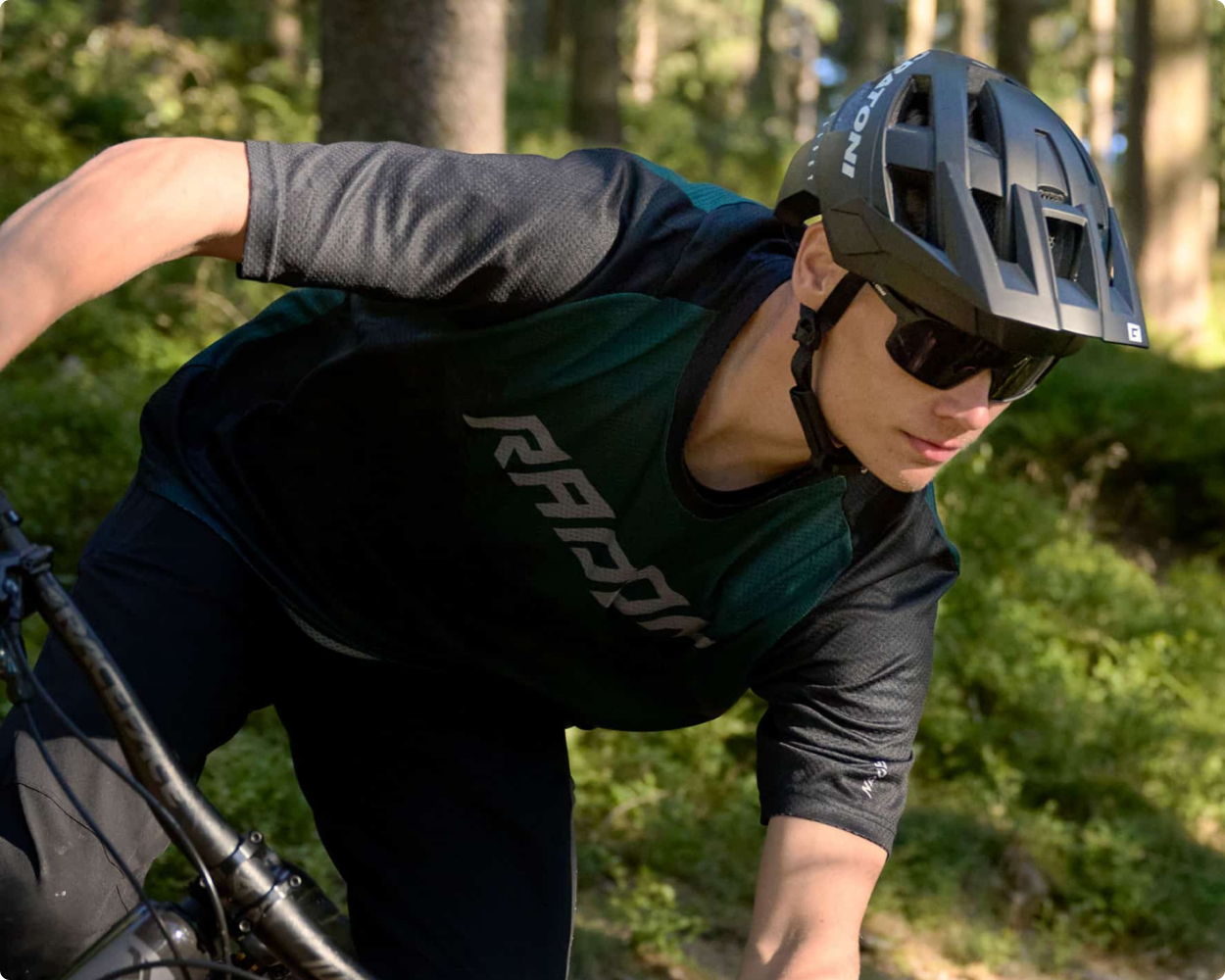 Ein Mountainbiker in voller Ausrüstung sitzt auf einem Mountainbike und trägt einen Helm von Cratoni zum Schutz bei seiner Fahrt durch den Wald