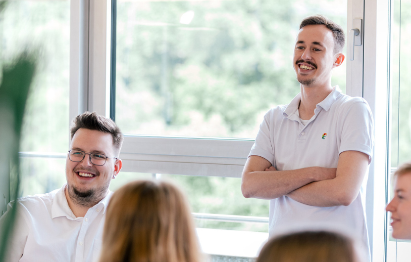 Ein Bild verschiedener Mitarbeiter die im Büro stehen und sich besprechen