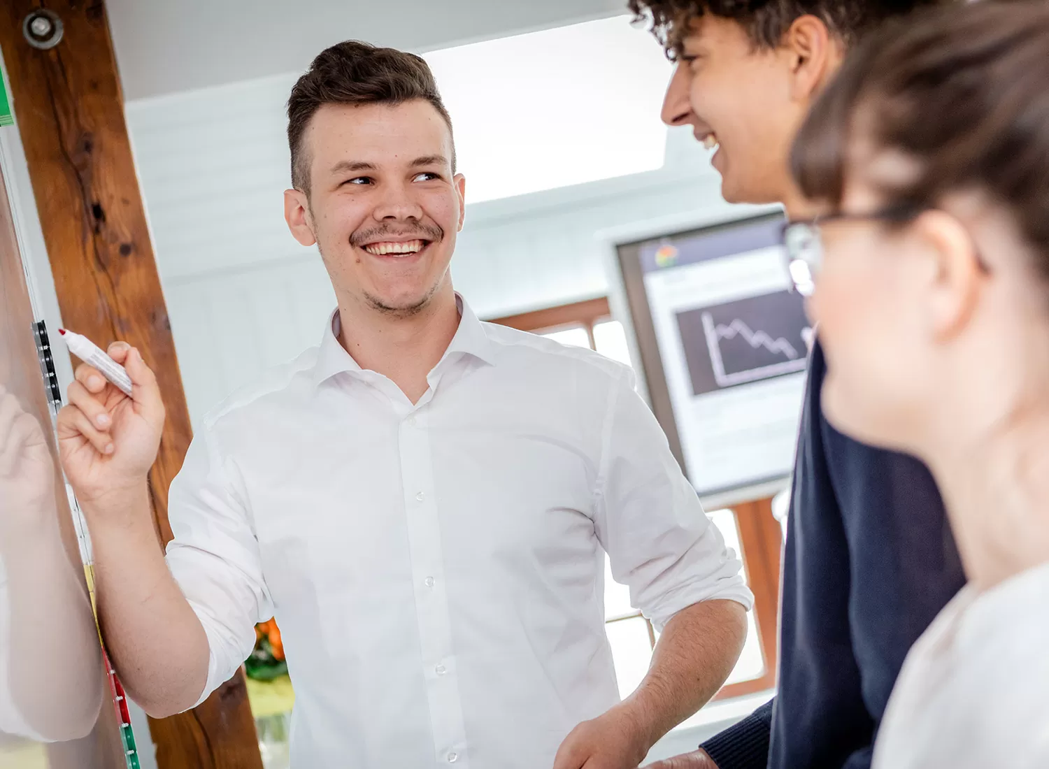 Drei Mitarbeitende besprechen ein Thema an einem Whiteboard