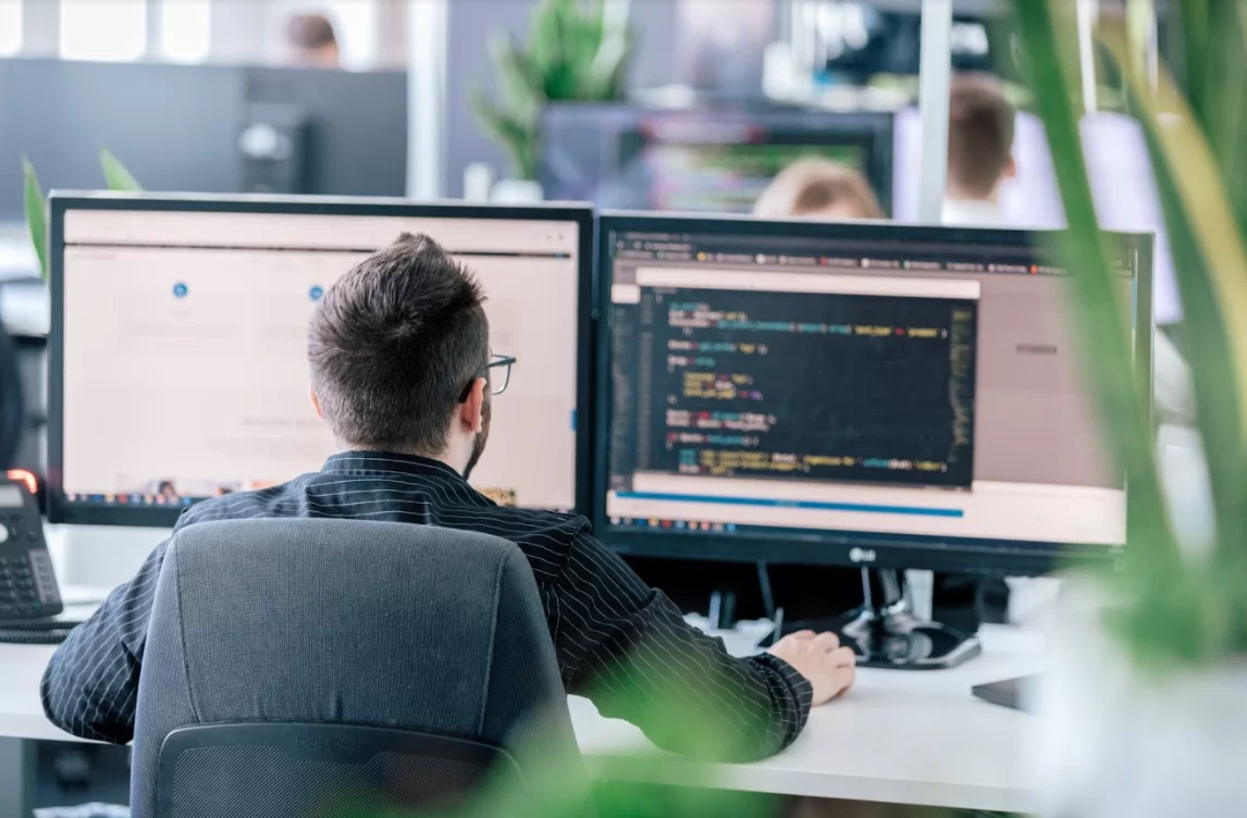 Ein Mann sitzt vor einem Bildschirm und programmiert