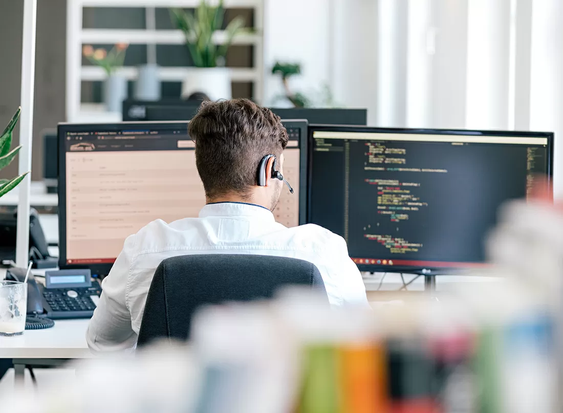 Ein Mitarbeiter sitzt vor seinem Arbeitsplatz und programmiert