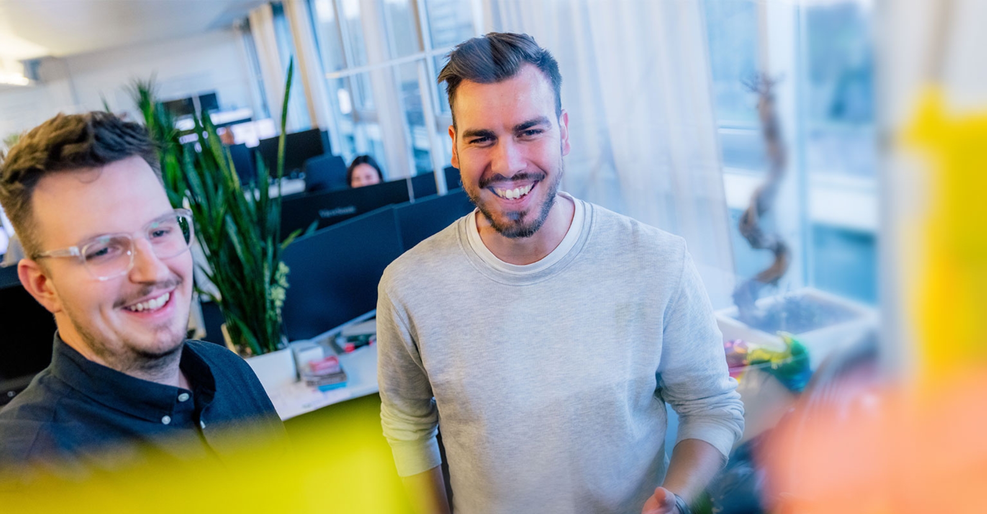 Zwei Mitarbeitende teilen einen Moment guter Laune im Büro