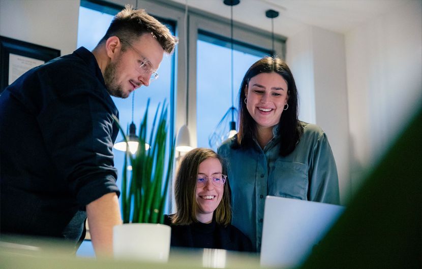 Drei Mitarbeiter halten eine Besprechung vor einem Laptop