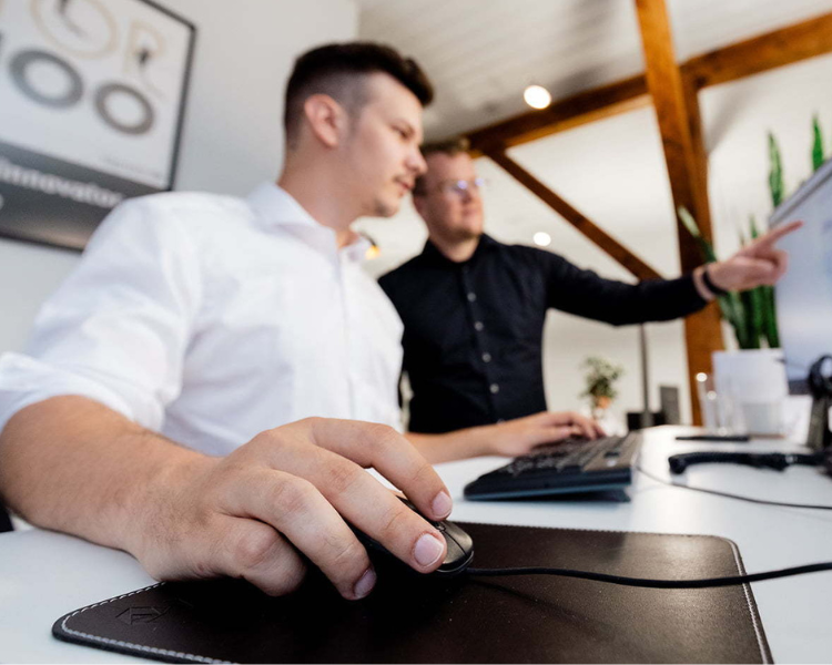 Zwei Mitarbeiter arbeiten zusammen an einem Computer in der Magento-Agentur