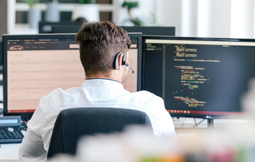 Entwickler programmiert in einer angenehmen Büroatmosphäre, während er in einer Online-Besprechung ist