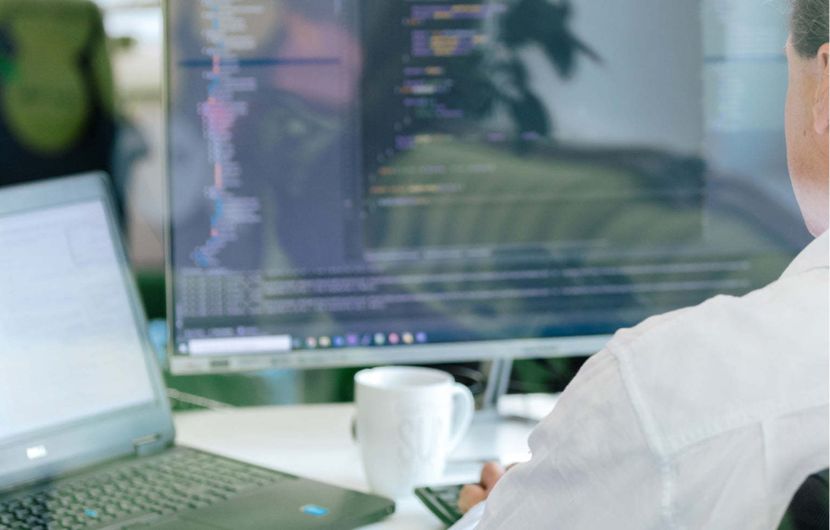 Entwickler sitzt am Computer und bearbeitet Quellcode