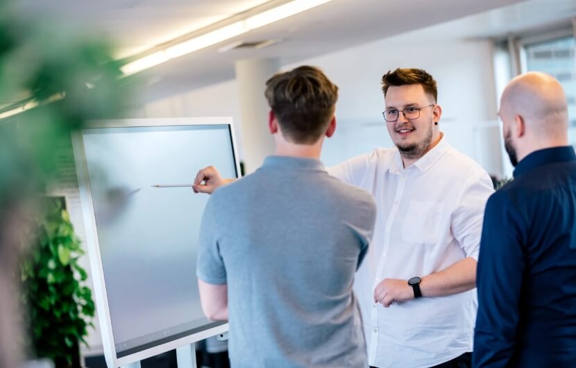 Mitarbeiter stehen an einem Smartboard und arbeiten an einem Responsive Design