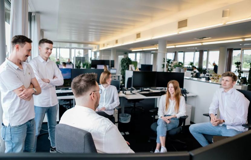 Individuelle Beratung durch SEA-Experten Ein erfahrener SEA-Experte berät einen Kunden an einem Schreibtisch mit Laptop und Monitor, auf dem Kampagnenstatistiken zu sehen sind – repräsentiert die individuelle Beratung einer professionellen SEA-Agentur.