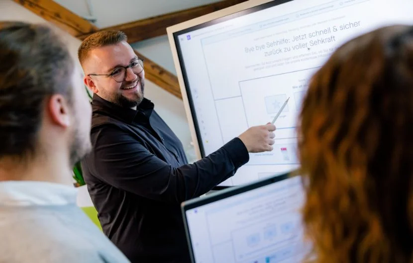 Ihre SEO-Agentur in Heidelberg Ein Mitarbeiter zeigt zwei weiteren eine Präsentation auf einem Whiteboard