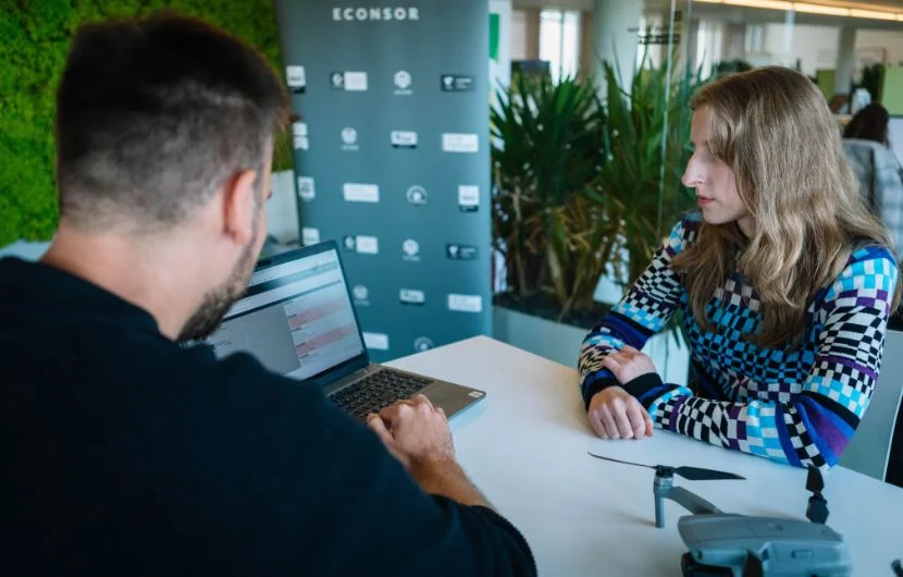 Ihre SEO-Agentur in Nürnberg Zwei Mitarbeiter sitzen am Tisch und schauen sich gemeinsam etwas auf einem Laptop an.