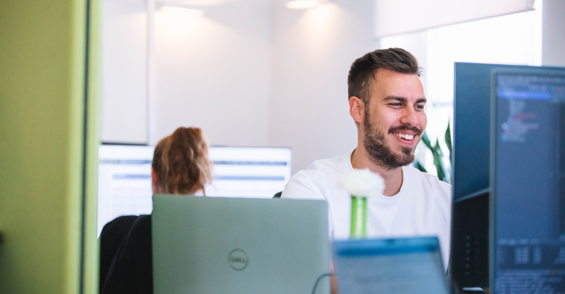 Lächelnder Mitarbeiter arbeitet motiviert am Bildschirm