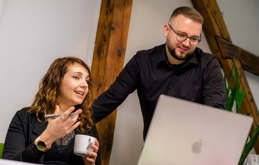 Zwei Mitarbeiter sind im Besprechungszimmer und unterhalten sich