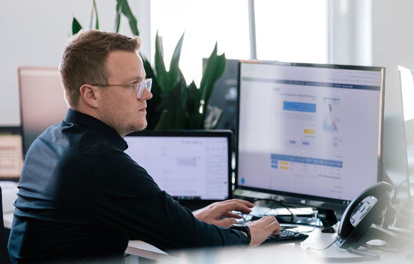 Ein Entwickler bearbeitet eine E-Commerce-Webseite auf mehreren Bildschirmen und passt die Benutzeroberfläche an.