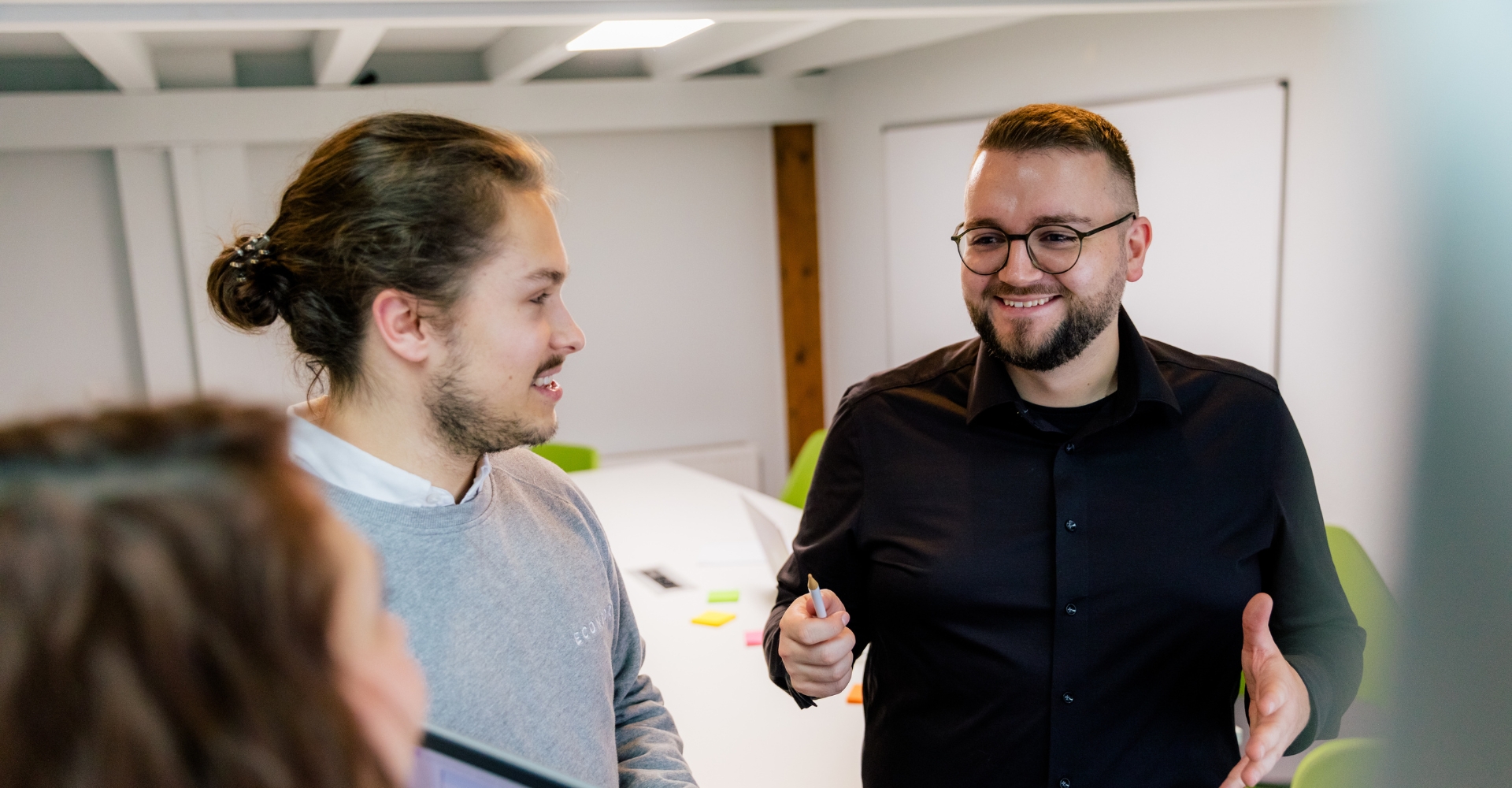 Drei Teammitglieder im Gespräch während einer Besprechung.