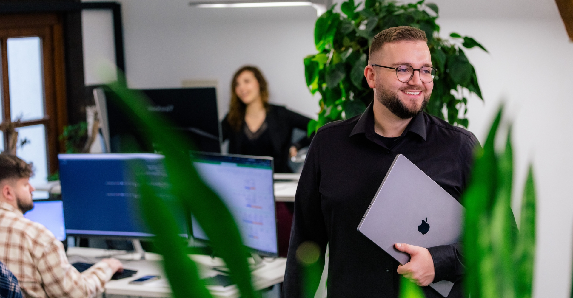 Teamleiter im Fokus, während das Team im Hintergrund arbeitet
