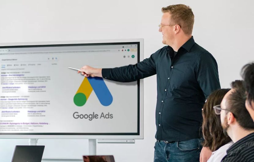 Zertifizierte Google-Ads SEA-Agentur ine Person präsentiert Google Ads Strategien vor einem großen Bildschirm in einem modernen Arbeitsumfeld, unterstützt durch sichtbare Zertifikate und Auszeichnungen – unterstreicht die Kompetenz einer zertifizierten Google-Ads SEA-Agentur.