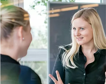 Zwei Mitarbeiterinnen der Shopware-Agentur im Gespräch, freundlicher Austausch in moderner Büroumgebung