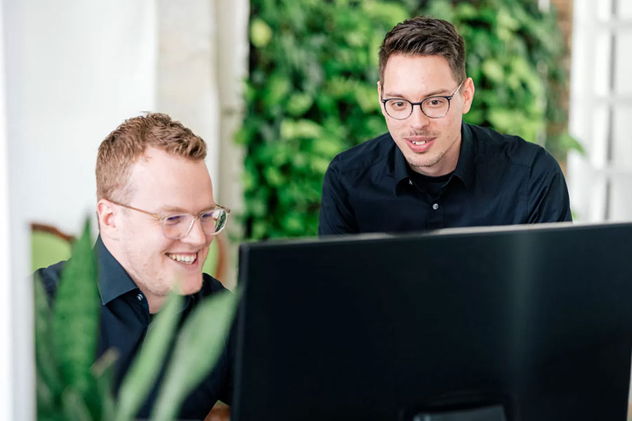 Zwei zertifizierte Magento-Experten schauen auf einen Bildschirm