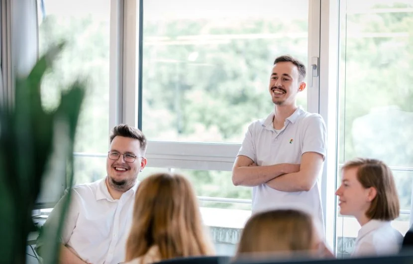 Ihre Online-Marketing-Agentur in Frankfurt Fünf Mitarbeiter sitzen in einem Besprechungszimmer, zwei davon lächeln.